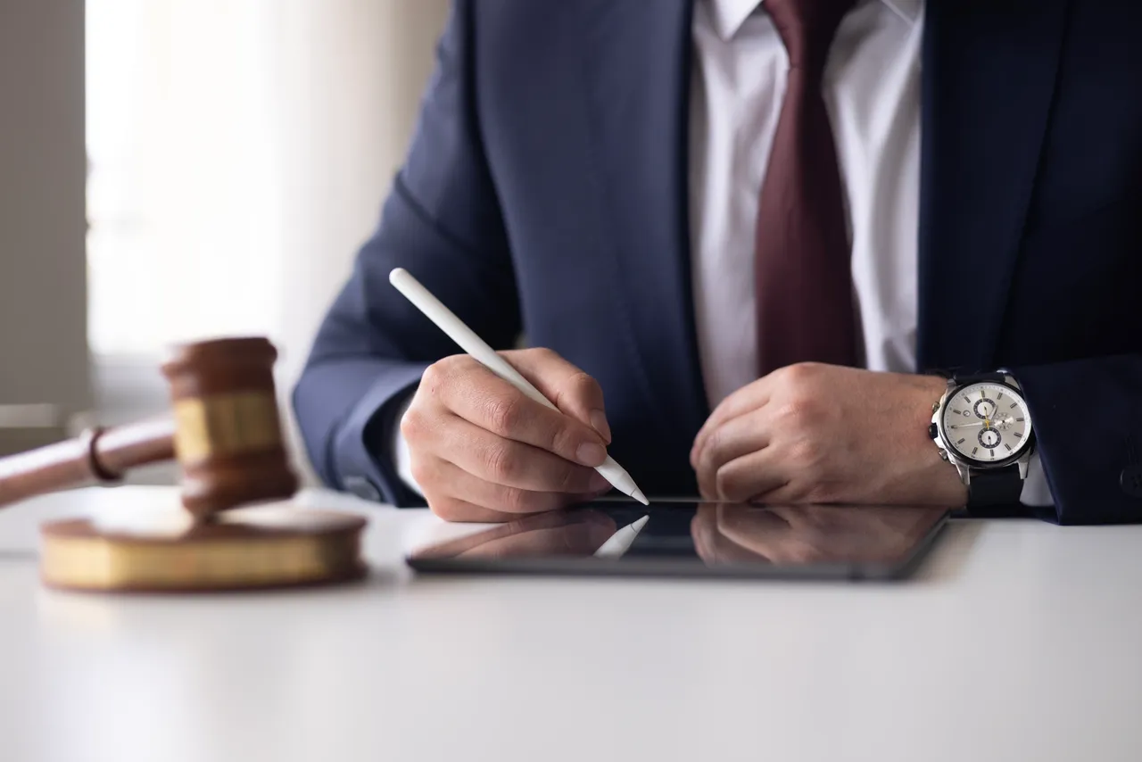 A professional signing documents on a tablet beside a gavel